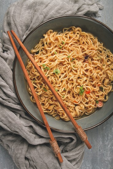 Instant noodles, in a bowl, on a gray table, top view, no people