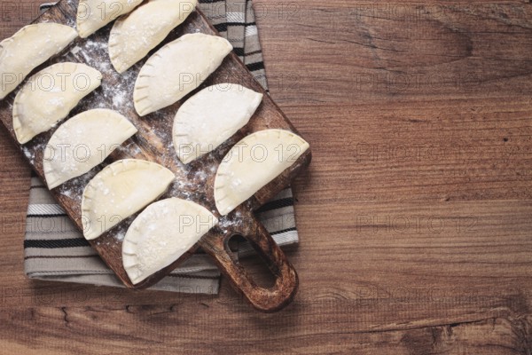 Traditional Polish dish, dumplings, raw, frozen, on a cutting board, wooden table, top view, no