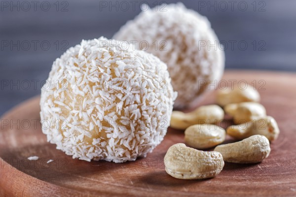 Energy balls cakes with coconut and cashew on wooden board on black background. selective focus,