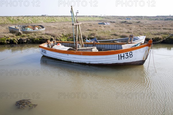 Small fishing boats moored in tidal inlet on the River Alde at Slaughden, Aldeburgh, Suffolk,