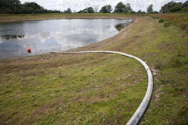 Irrigation pipe water reservoir lake at low level in summer Sutton, Suffolk, England, UK