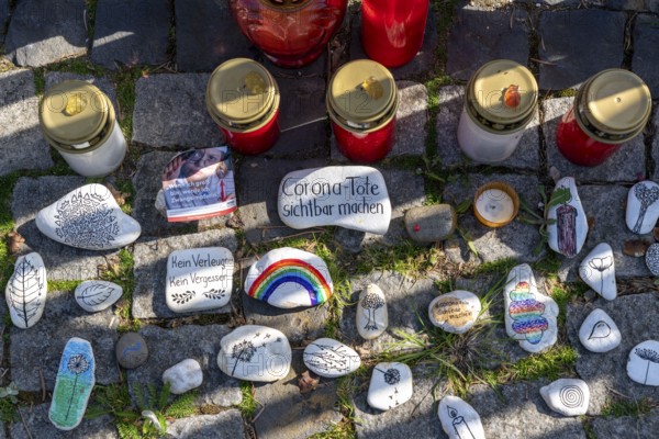 Candles and stones with inscriptions in memory of the dead of the corona pandemic, stickers from