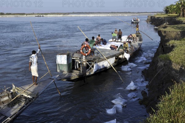 Public Works Department (PWD) of Assam labourer throwing sand bag from boat in the banks of Beki