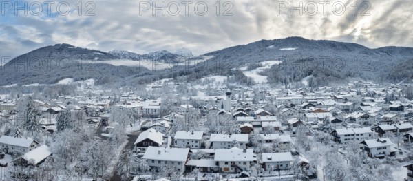 Snow-covered village in a mountain landscape under a cloudy sky, Bad Feilnbach