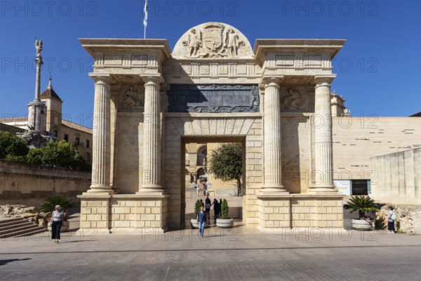 A monumental entrance with reliefs and columns under a blue sky, Cordoba