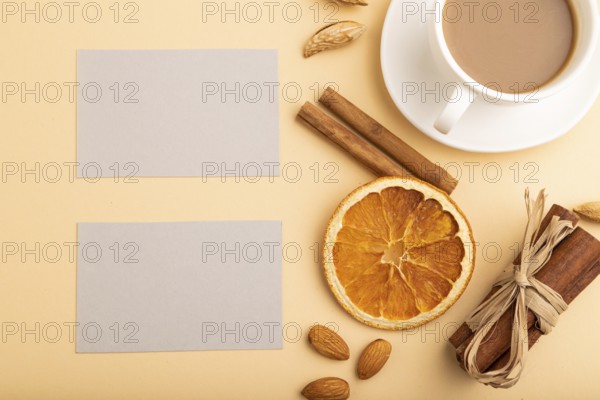 Composition of gray paper business cards, almonds, cinnamon and cup of coffee. mockup on orange