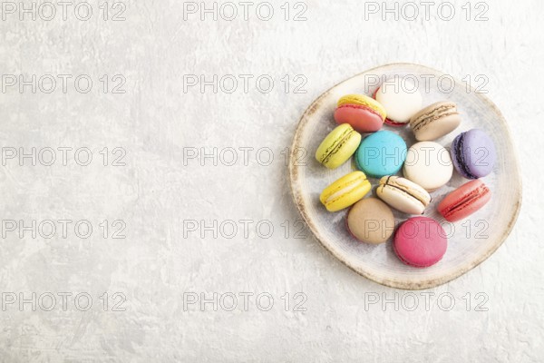 Multicolored macaroons on ceramic plate on gray concrete background. top view, copy space, still