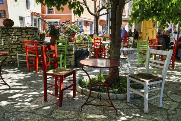 Terrace under trees, colourful chairs and tables in front of a café, small town Leonidi, Leonidio,