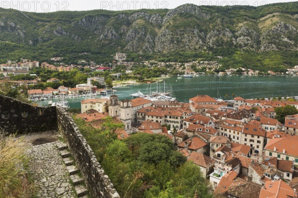 High angle view of walled mountainside walking trail, apartment buildings and houses covered with