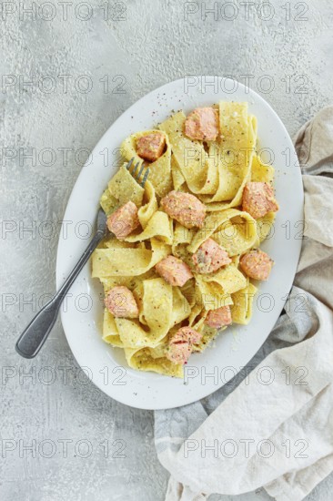 Papardelle pasta, in creamy sauce with salmon, natural light, lifestyle, homemade, on a gray