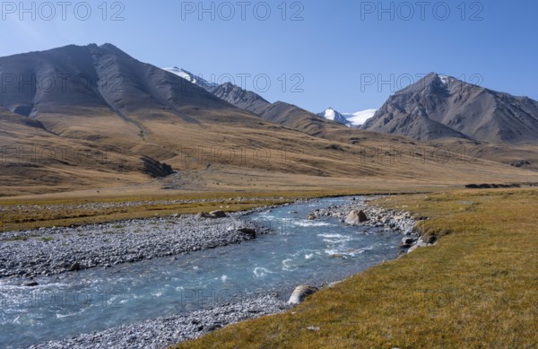Blue river in the Burkhan valley, mountain landscape with glaciated peaks and golden meadows,