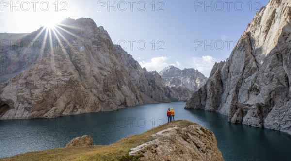Couple at the blue mountain lake between rocky steep mountain peaks, Sun Star, Kol Suu Lake, Sary