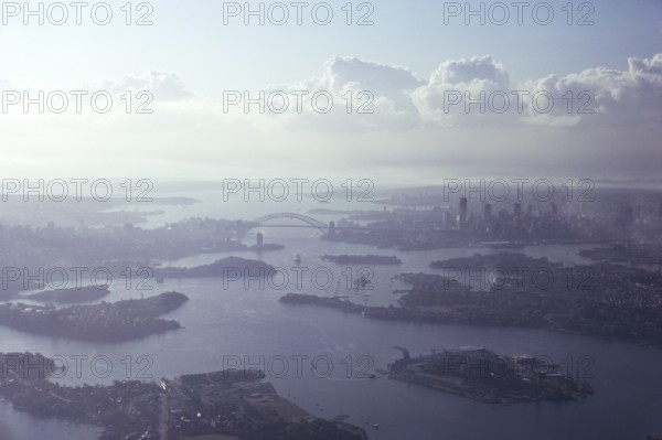 Oblique aerial view of the harbour, the bridge and the city centre skyline, Sydney, Australia 1974