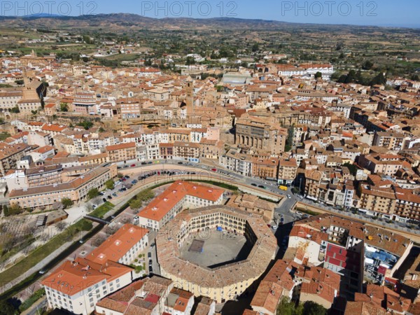 Aerial view of a historic town with tiled roofs and a central square in the middle of a hilly
