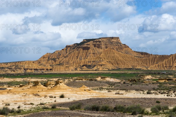 Majestic mountain in a dry desert landscape, partly cloudy with scattered green vegetation against