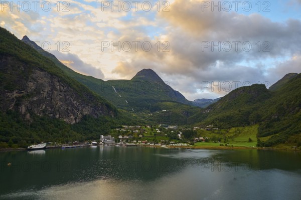 Geiranger with fjord landscape with mountains embedded in nature, covered by dramatic clouds,