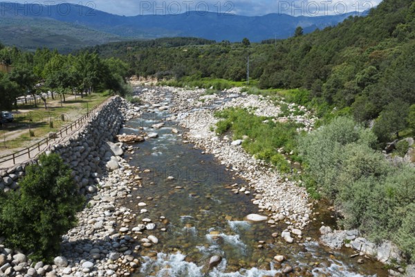 Landschaft mit einem gebirgigen Fluss, der durch eine grüne und steinige Landschaft fließt, umgeben