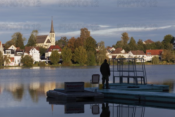 View over the town lake to Bad forest lake, man on a footbridge, morning light, Bad forest lake,