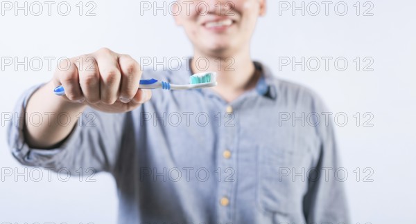 Smiling person showing toothbrush with toothpaste isolated. Unrecognizable man holding brush with