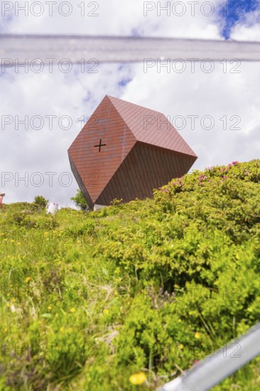 A modern metal chapel sits on a green hill under a cloudy sky, Penken, Zillertal, Austria, Europe