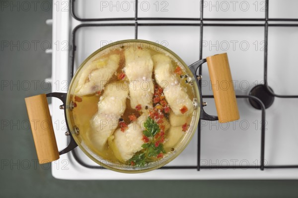 A pot of white fish fillets simmers slowly in clear broth, garnished with herbs and spices. The