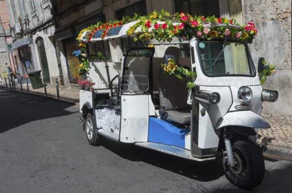 Tuk-tuk decorated with colourful flowers on empty city street, presented in summer light, Old Town,