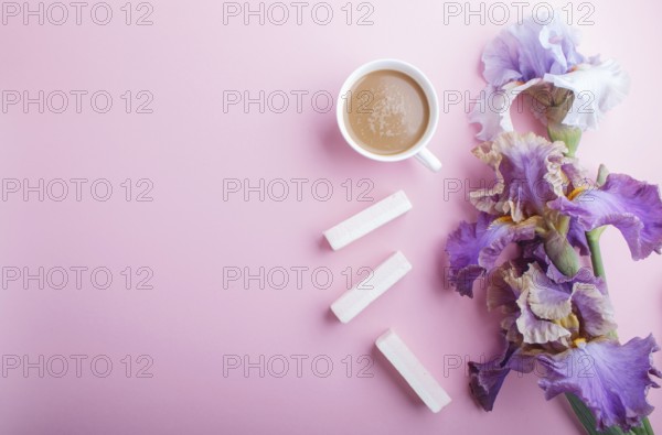 Purple iris flowers and a cup of coffee on pastel pink background. Morninig, spring, fashion