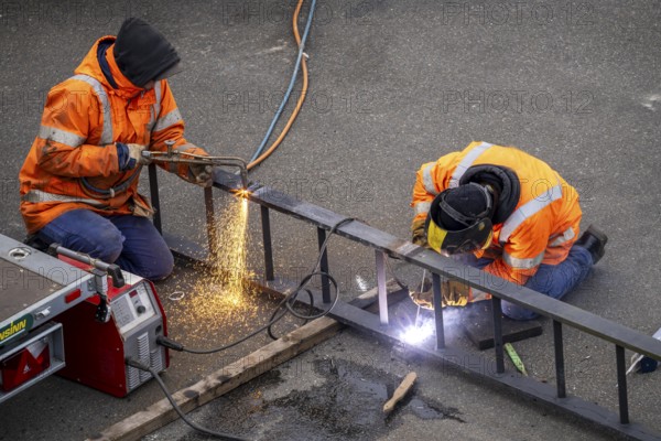 Locksmith at work, cutting and welding, on a workpiece in an industrial plant, a metal ladder is