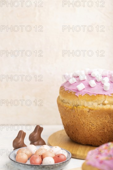 Homemade glazed and decorated easter pies with chocolate eggs and rabbits on a white concrete