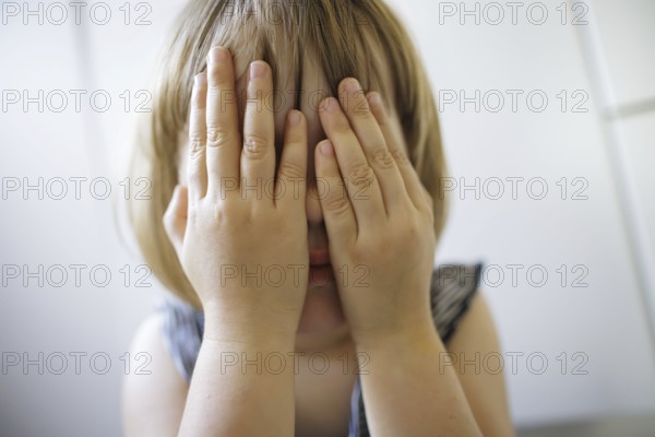 Symbolic photo on the subject of fear in children (posed scene) . A little girl holds her hands in
