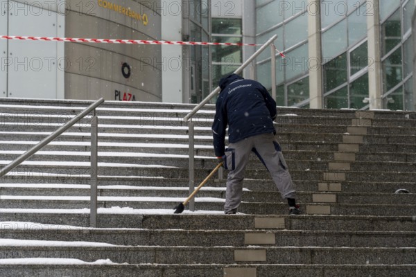 Onset of winter, winter service, clearing snow on the stairs of the Commerzbank building,