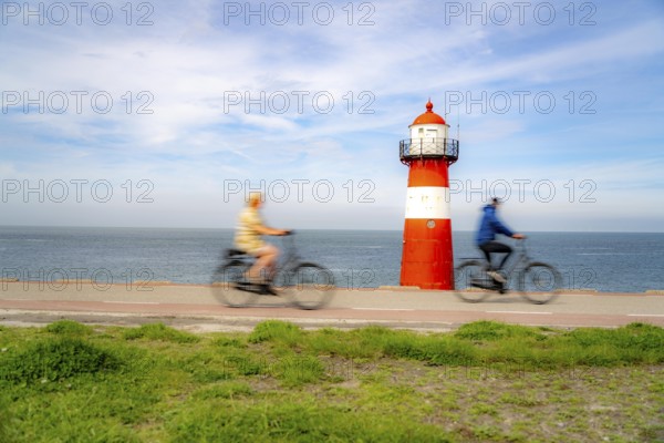 North Sea dyke near Westkapelle, Westkapelle Laag lighthouse, cyclists on the Zeeuwse Wind Route