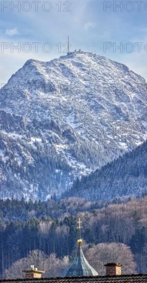 Snow-covered mountain with a church in the foreground under a clear blue sky, Bad Feilnbach