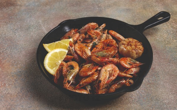 Fried shrimps, in a cast-iron pan, shrimps for beer, in a newspaper, on a gray table, there are no