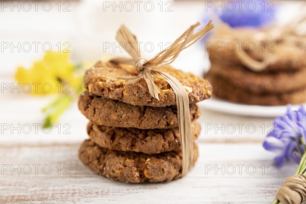 Oatmeal cookies with spring snowdrop flowers bluebells, narcissus and cup of coffee on white wooden