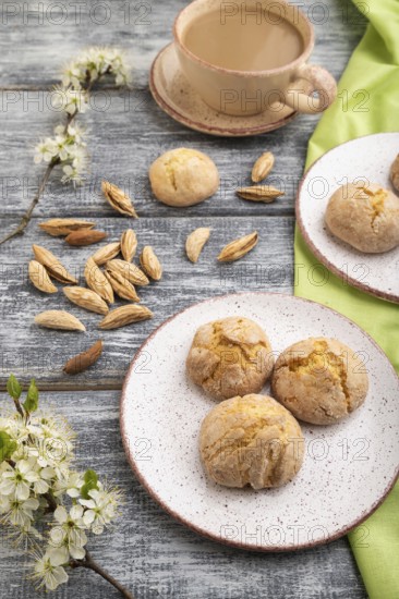 Almond cookies and a cup of coffee on a gray wooden background and green linen textile. Side view,