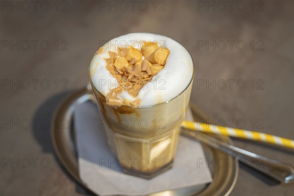 A glass of latte with creamy topping and biscuit crumbs on a serving tray, autumn creations, Cafe