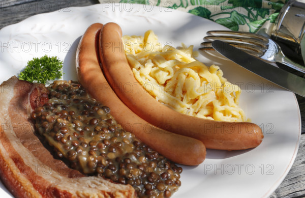 Swabian cuisine, lentils with spaetzle, pancetta and string sausages, meat arranged on a plate,