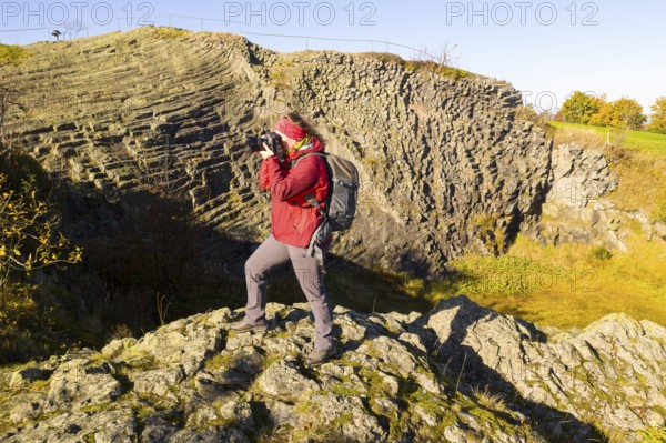 Photographer with camera and rucksack taking pictures at Hirtstein, Marienberg, Saxony, Germany,
