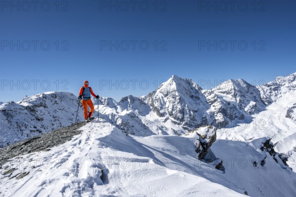 Ski tourers on foot, snow-covered mountain landscape in winter, view of mountain peaks