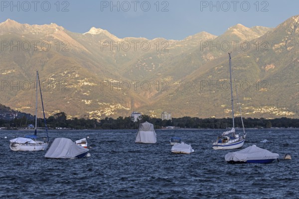 Boats lying in the water, Locarno, Lake Maggiore, surrounding mountains in the evening light,