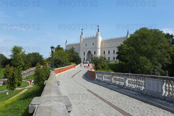 Path leads to a castle with towers and battlements, surrounded by trees and greenery, castle with