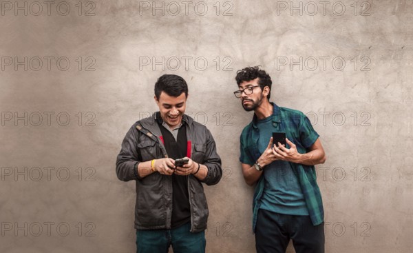 Man spying on another guy cell phone near him. Gossipy man spying on his friend cell phone. Man