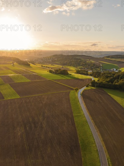 Sprawling fields in the evening light with a winding road under a warm glowing sunset, Gechingen,