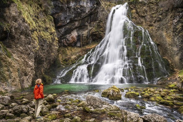 A hiker at the Gollinger waterfall (Schwarzbachfall, Schwarzenbachfall) in autumn. Rocks with moss.