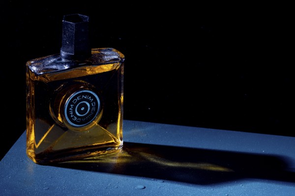 Bottle with aftershave in dark light, elegant style with blue background