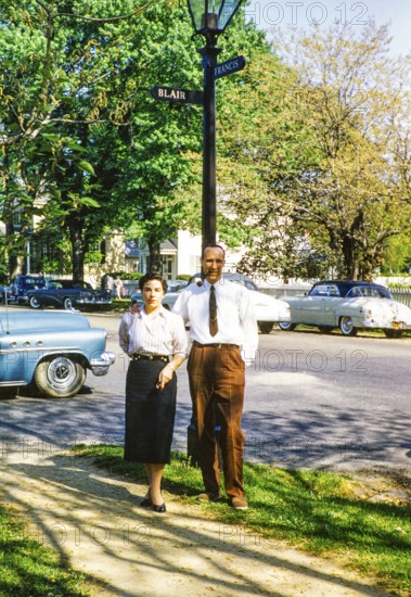 Full-length portrait of an elegantly dressed man and woman standing on the street next to a