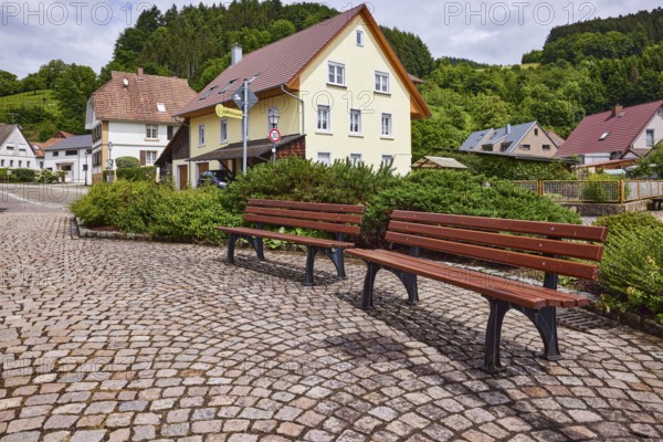 Benches, pavement made of cobblestones, car park, multi-family houses, hilly landscape with