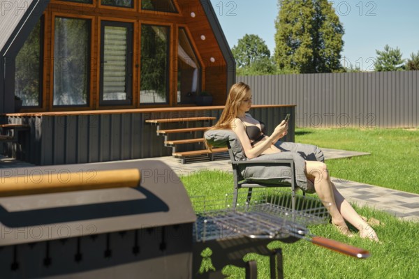 Serene woman enjoying a peaceful moment on a sun lounger in the backyard of a modern A-frame house