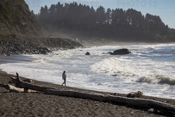 Crescent City, California - A woman walks on the beach of the Pacific Ocean in northern California